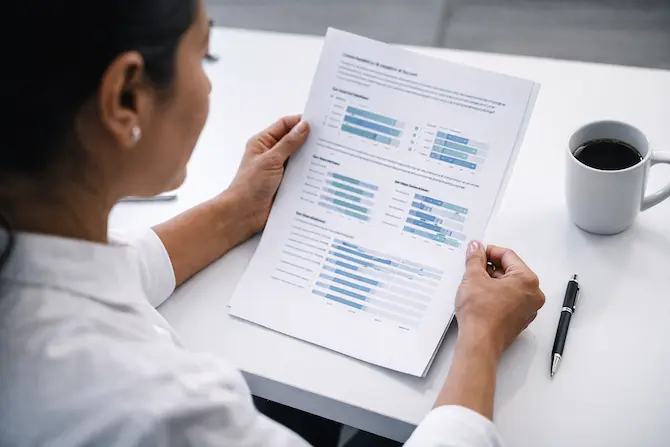 Especialista en recursos humanos analizando reporte de evaluación psicométrica con gráficas de percentiles y resultados por competencia