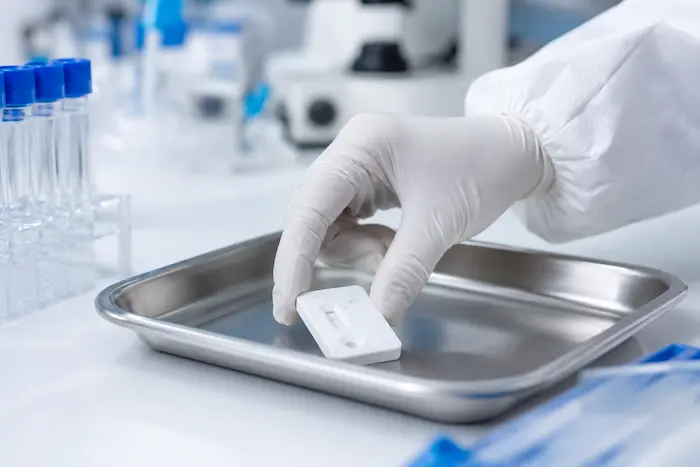 Manos con guantes realizando prueba rápida de antígeno en laboratorio clínico certificado